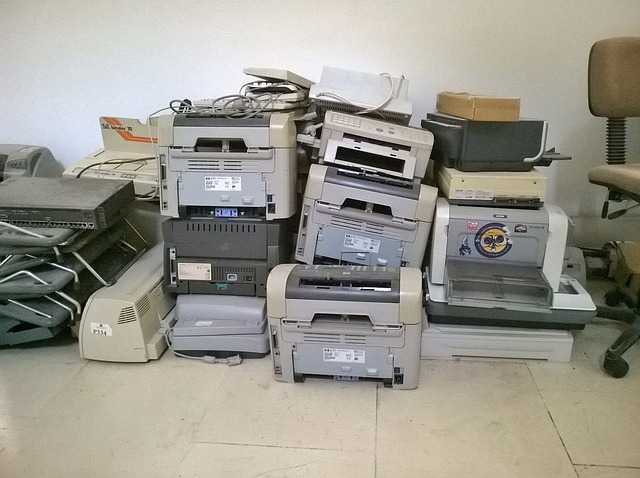 Stampanti, fotocopiatrici e monitor dismessi accatastati in un locale, apparecchiature elettriche fuori uso da avviare al recupero